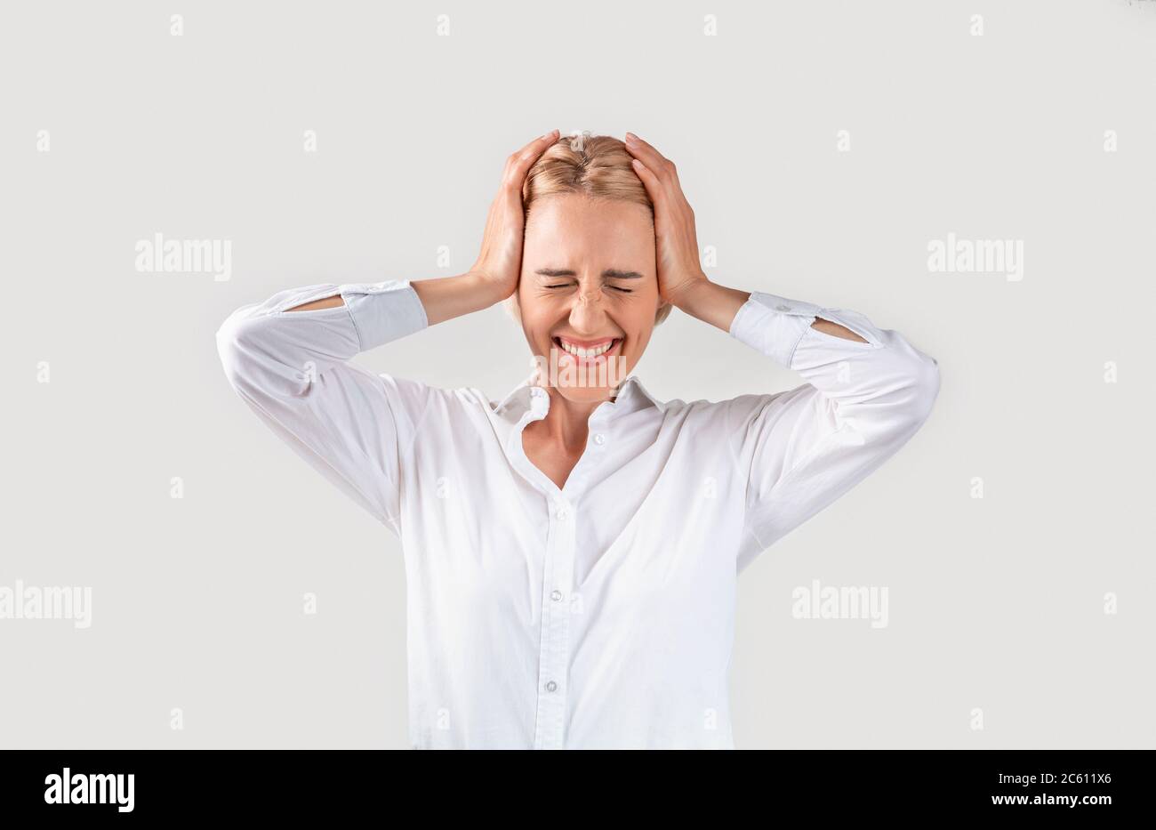 Emotional mature businesswoman holding her head in disbelief on light background Stock Photo
