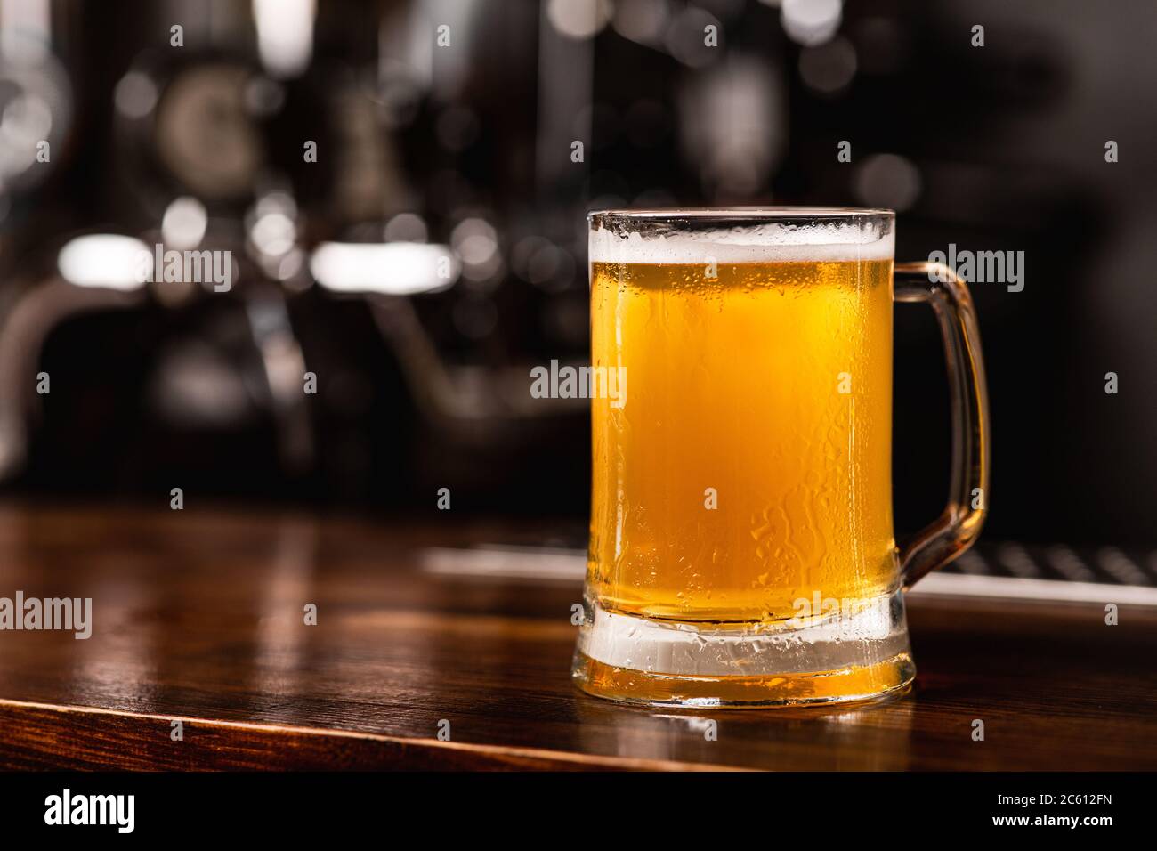 Favorite fresh beer from keg. Mug of light ale on wooden bar counter on blurred background Stock Photo