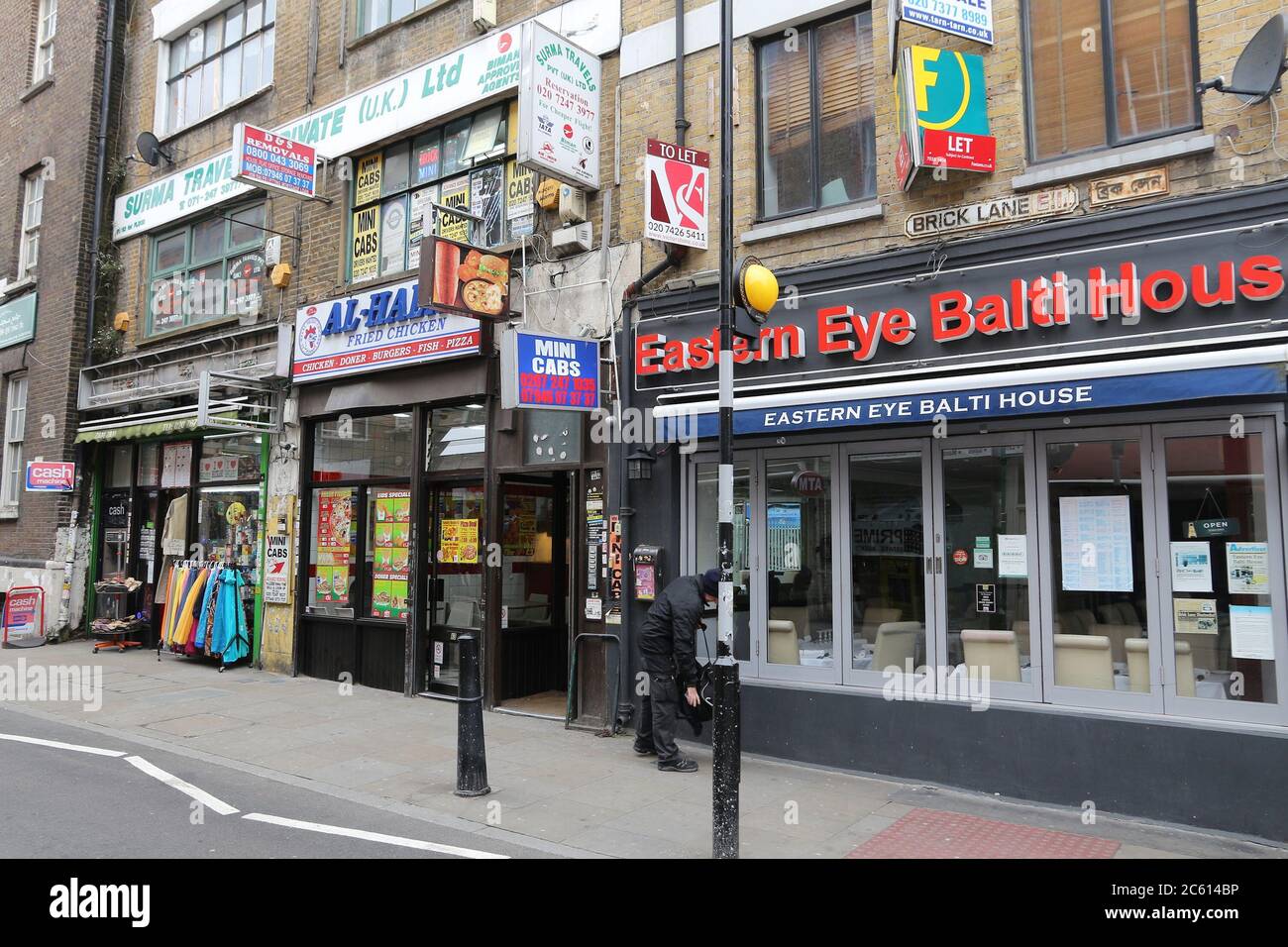 LONDON, UK - APRIL 22, 2016: People walk by ethnic stores and restaurants at Brick Lane, Shoreditch, London. Shoreditch is known for its multicultural Stock Photo