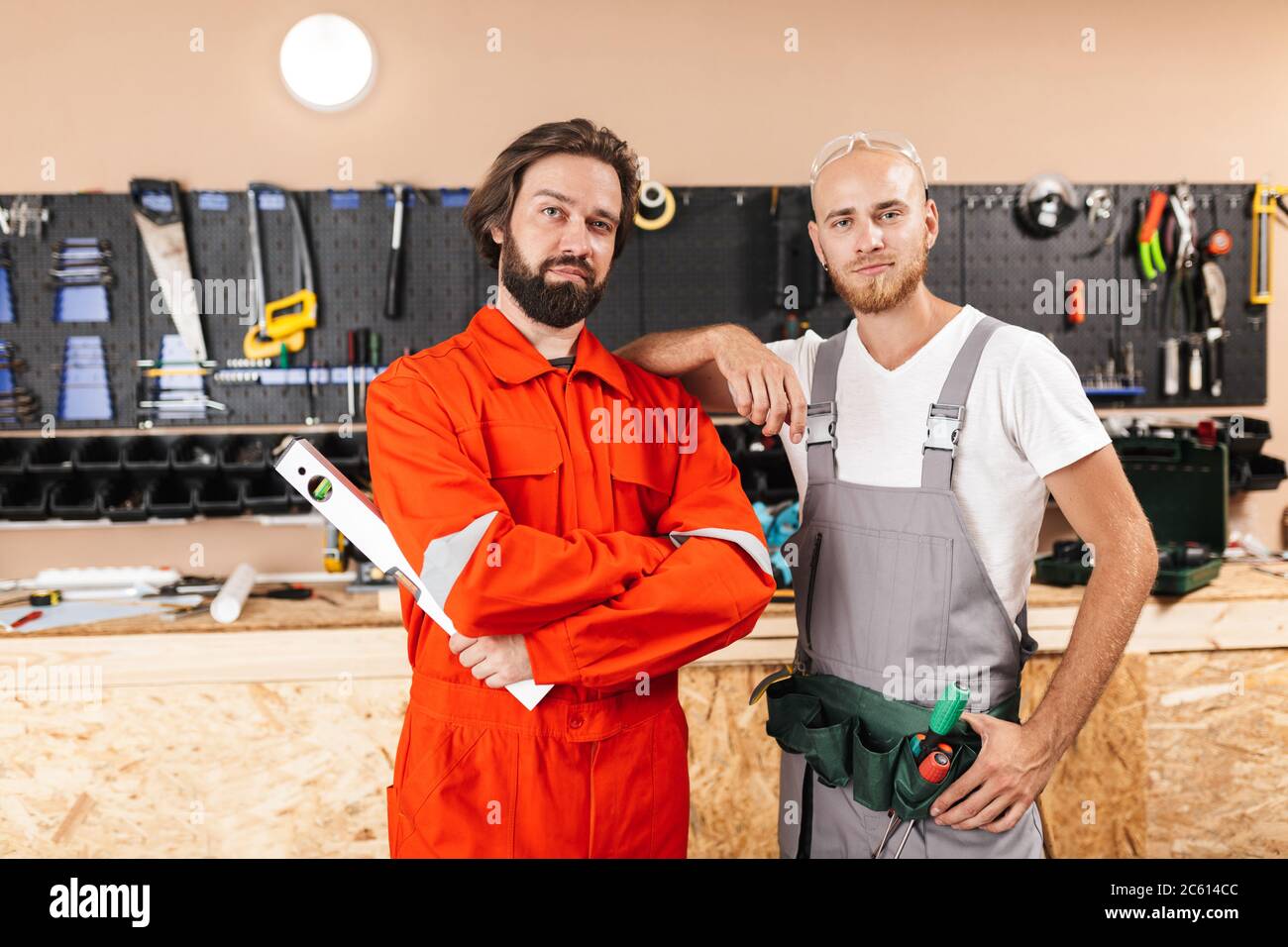 Two builders in work clothes thoughtfully looking in camera spen Stock Photo