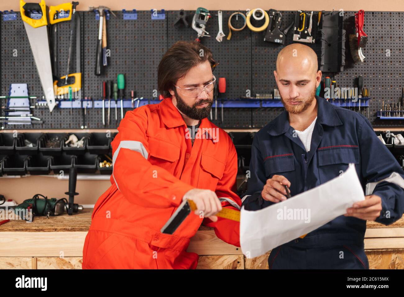 Two builders in work clothes thoughtfully working on sketch with Stock Photo