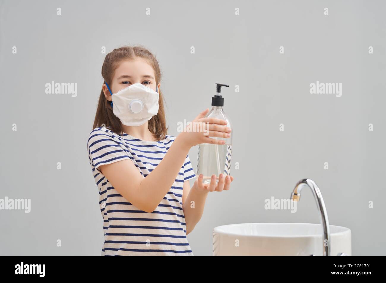 Girl is wearing face mask and washing hands during coronavirus and flu outbreak. Virus and illness protection, home education and quarantine. COVID-20 Stock Photo