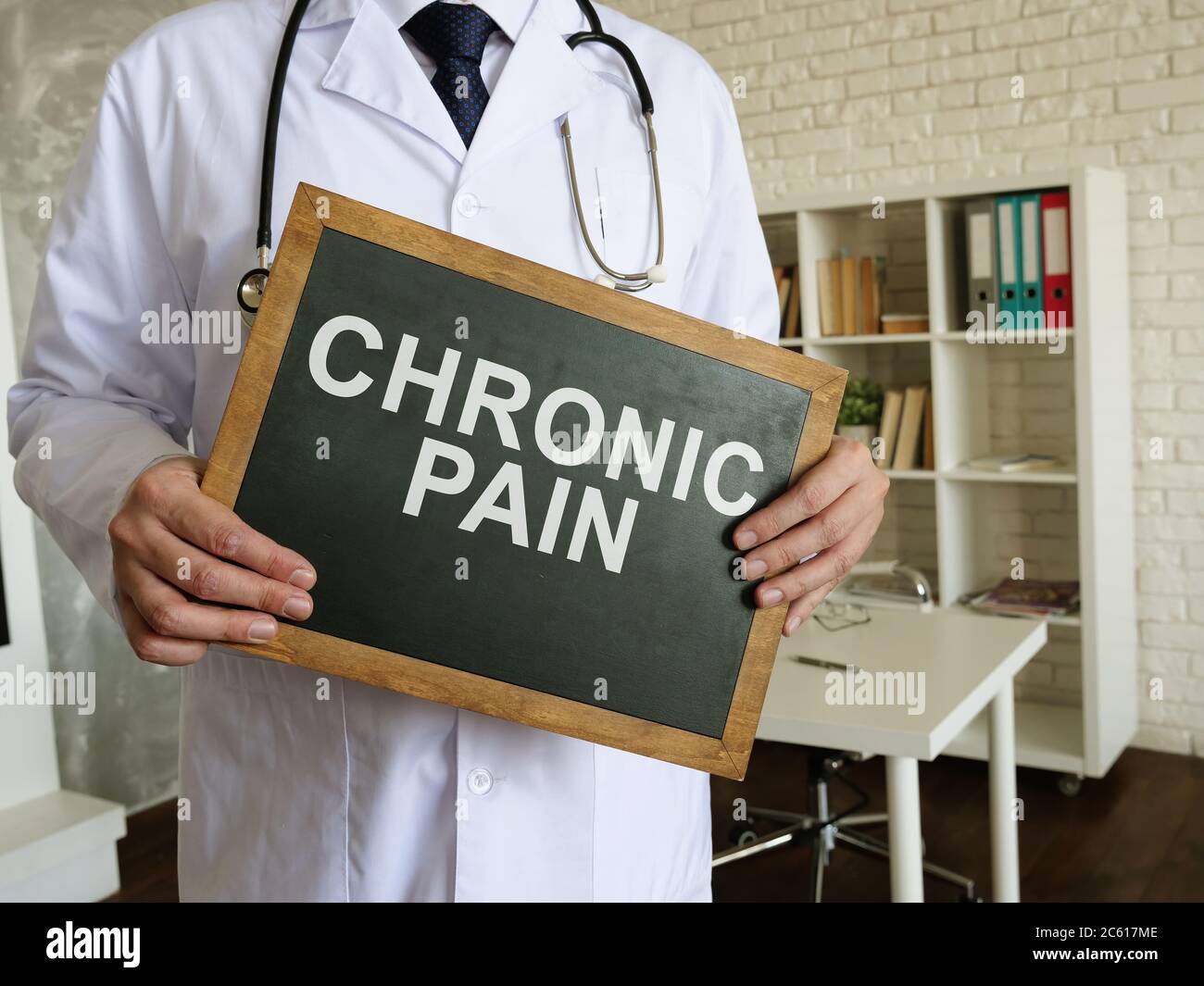Doctor holds blackboard with words chronic pain. Stock Photo