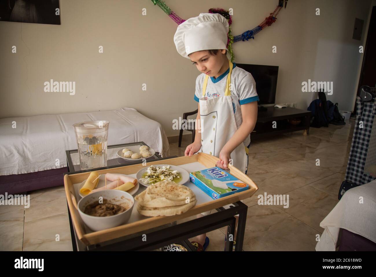 Cairo, Egypt. 17th June, 2020. Malek wears chef costume while helping his mother preparing breakfast. For more than three months schools, sports clubs, amusement parks and gardens have been closed due to the coronavirus pandemic. The majority of children suddenly got stuck at home where they are trying to come up with activities to kill their time, however, they still have hopes that soon enough they can spend their leisure time in open spaces instead of home confinement. Credit: Lobna Tarek/dpa/Alamy Live News Stock Photo
