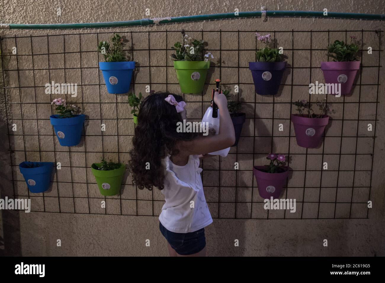 18 June 2020, Egypt, Cairo: Layan waters the plants which her mother hanged on the wall at their house backyard. For more than three months schools, sports clubs, amusement parks and gardens have been closed due to the coronavirus pandemic. The majority of children suddenly got stuck at home where they are trying to come up with activities to kill their time, however, they still have hopes that soon enough they can spend their leisure time in open spaces instead of home confinement. Photo: Lobna Tarek/dpa Stock Photo