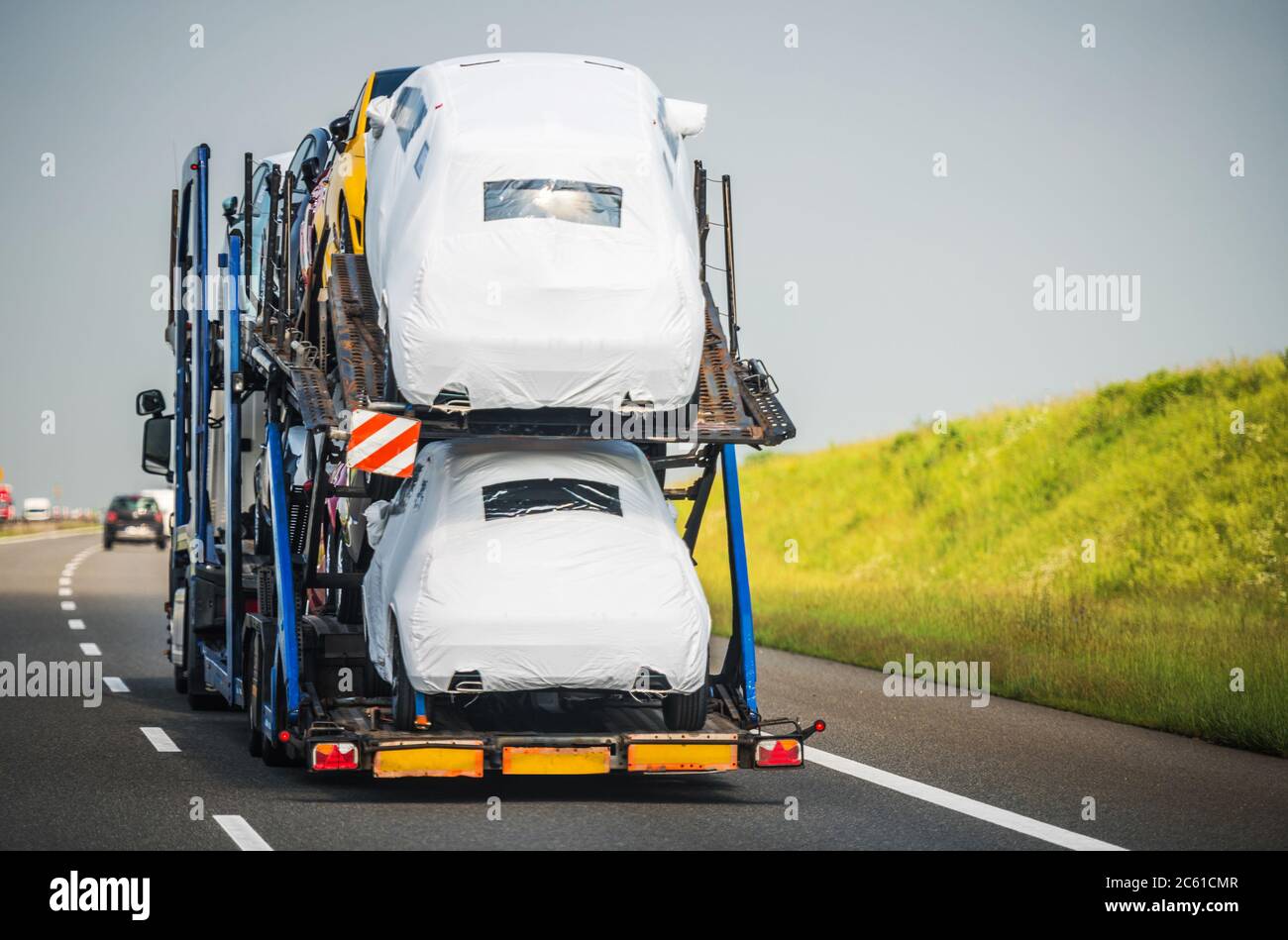 Car Carrier Trailer Full of Vehicles Driving Down the Highway. Car Hauler Semi Truck Vehicle Transportation. Stock Photo