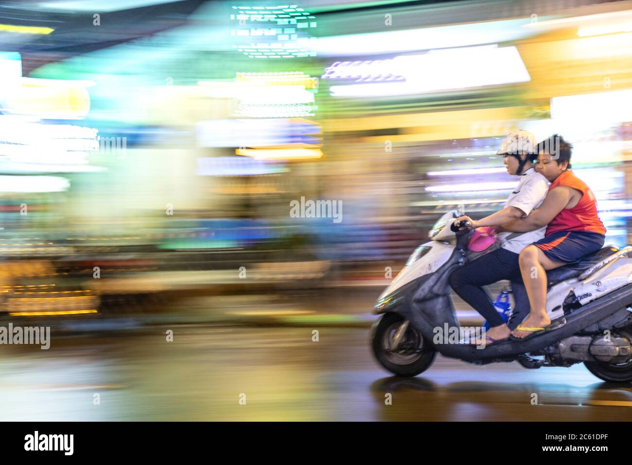 A speeding motorbike in an Asian city centre Stock Photo