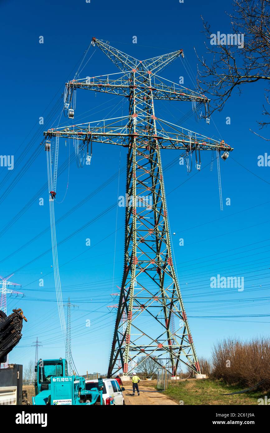 Arbeiter auf einem Hochspannungsmast vor blauem wolkenlosen Himmel Stock Photo