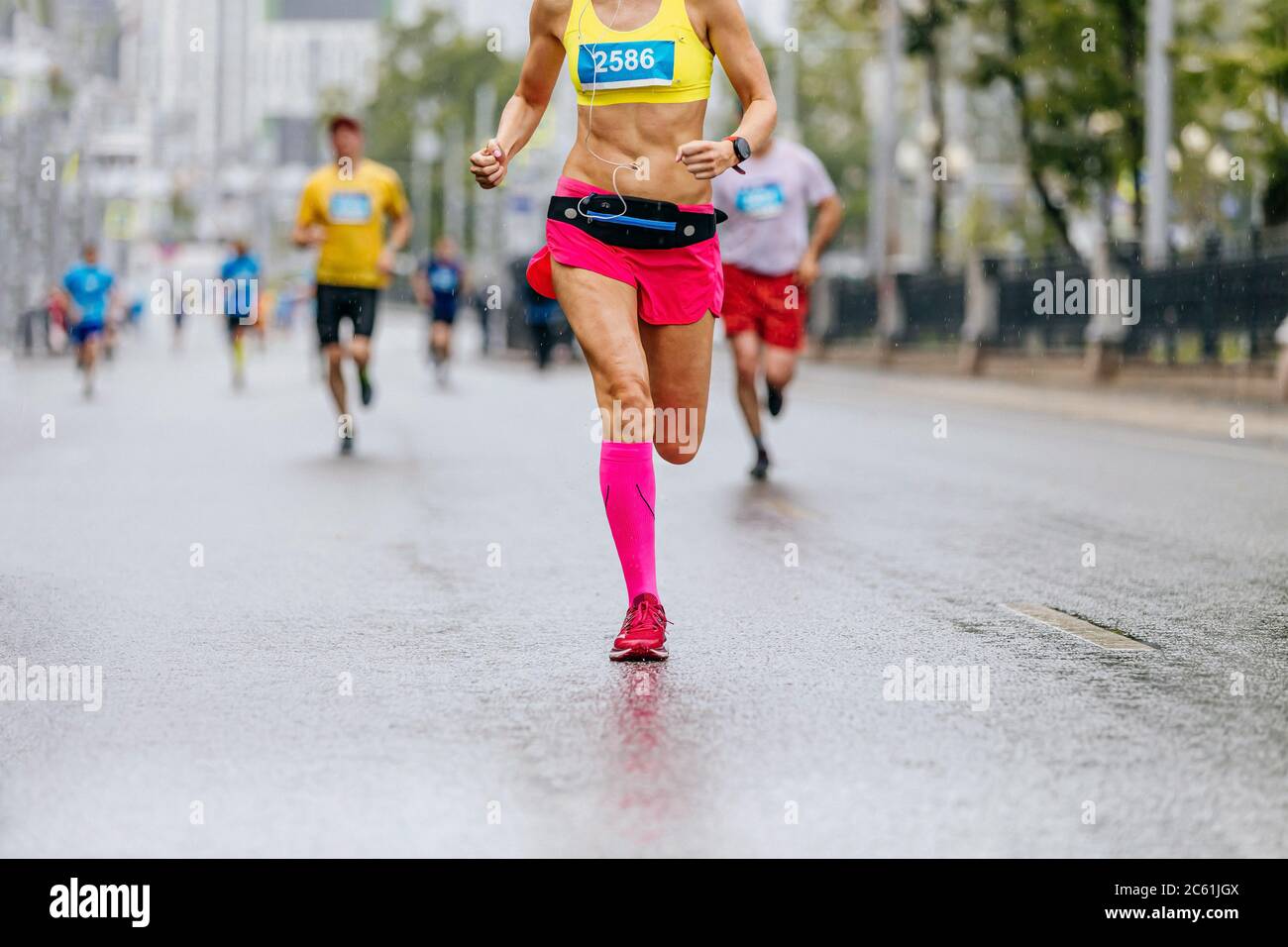 legs female runner in pink compression socks run in rain on wet road