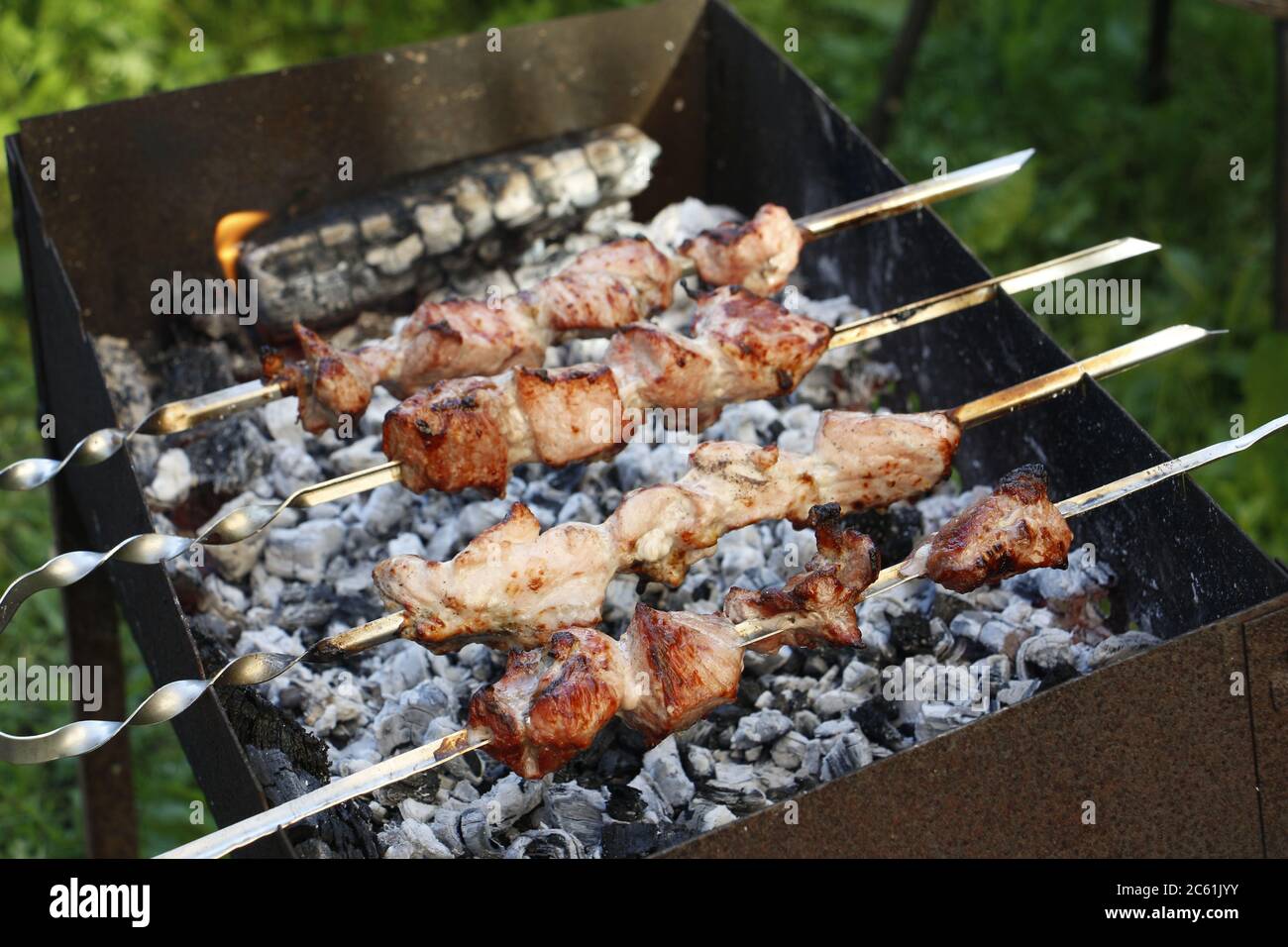 Cooking barbecue skewers. Marinated kebab is grilled on charcoal. Shish kebab barbecue was made of lamb, pork, beef, chicken. Roast beef skewers on ba Stock Photo