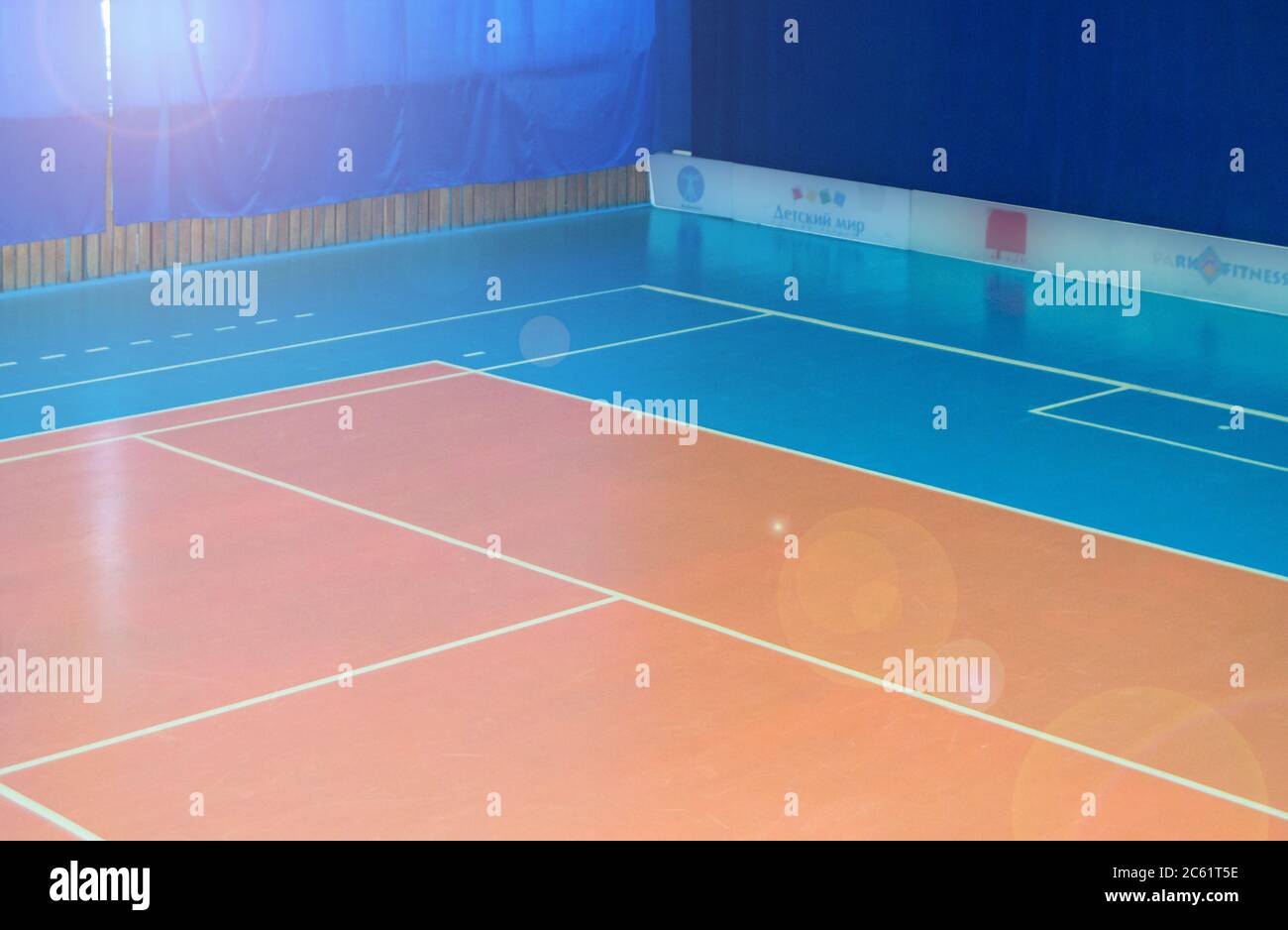 An empty gym with a volleyball court, floor markings for sports games