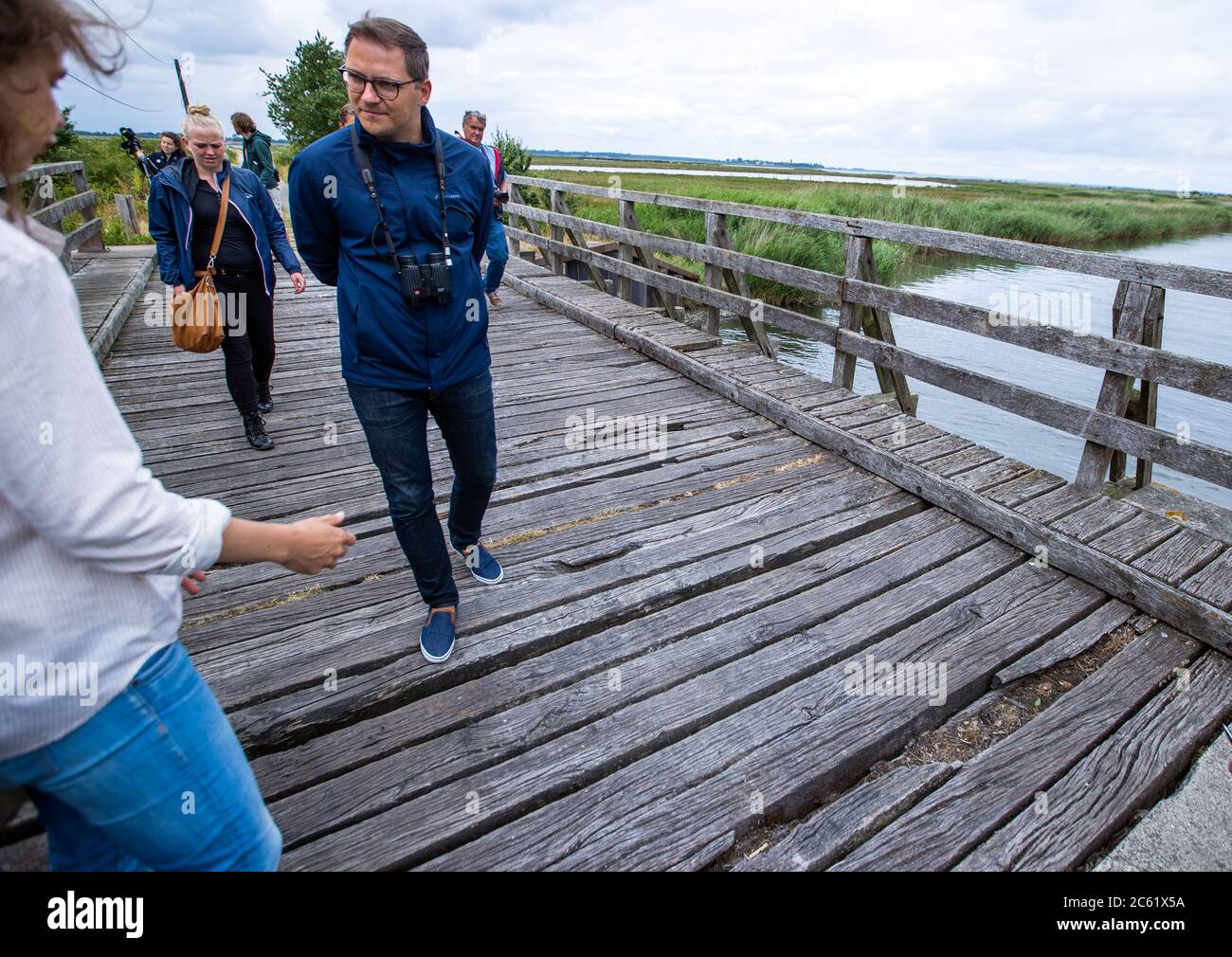 02 July 2020, Mecklenburg-Western Pomerania, Greifswald: Patrick Dahlemann (SPD), the Parliamentary State Secretary for Western Pomerania, crosses a rather dilapidated wooden bridge as access to the nature conservation island Koos in the Greifswald Bodden. After the renaturation, animal and plant species that were thought to be lost have returned to the island in recent years. The Succow Foundation was established in 1999 as the first non-profit nature conservation foundation in the new federal states of Germany. In 2016 it took over 365 hectares on the island and in the Karrendorf meadows on Stock Photo