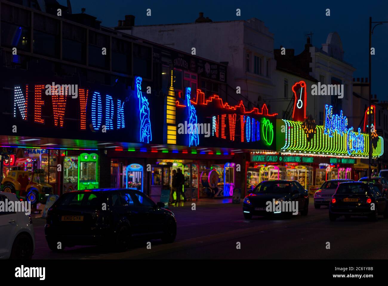 Amusement arcades illuminated along Marine Parade, Southend on Sea, Essex, UK. Night time view of New York amusements with parked cars Stock Photo