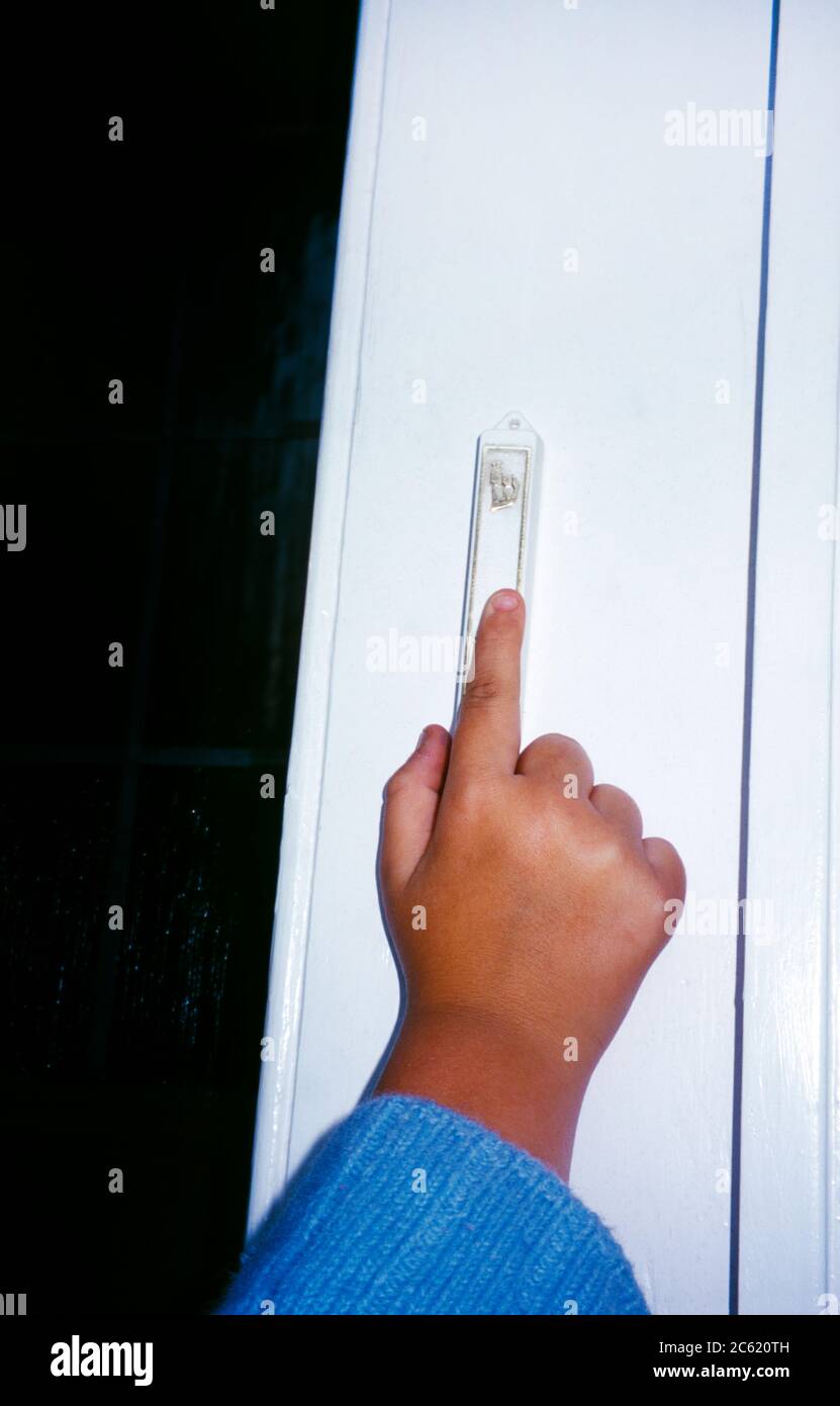A Child Touching The Mezuzah on a door frame before entering a room