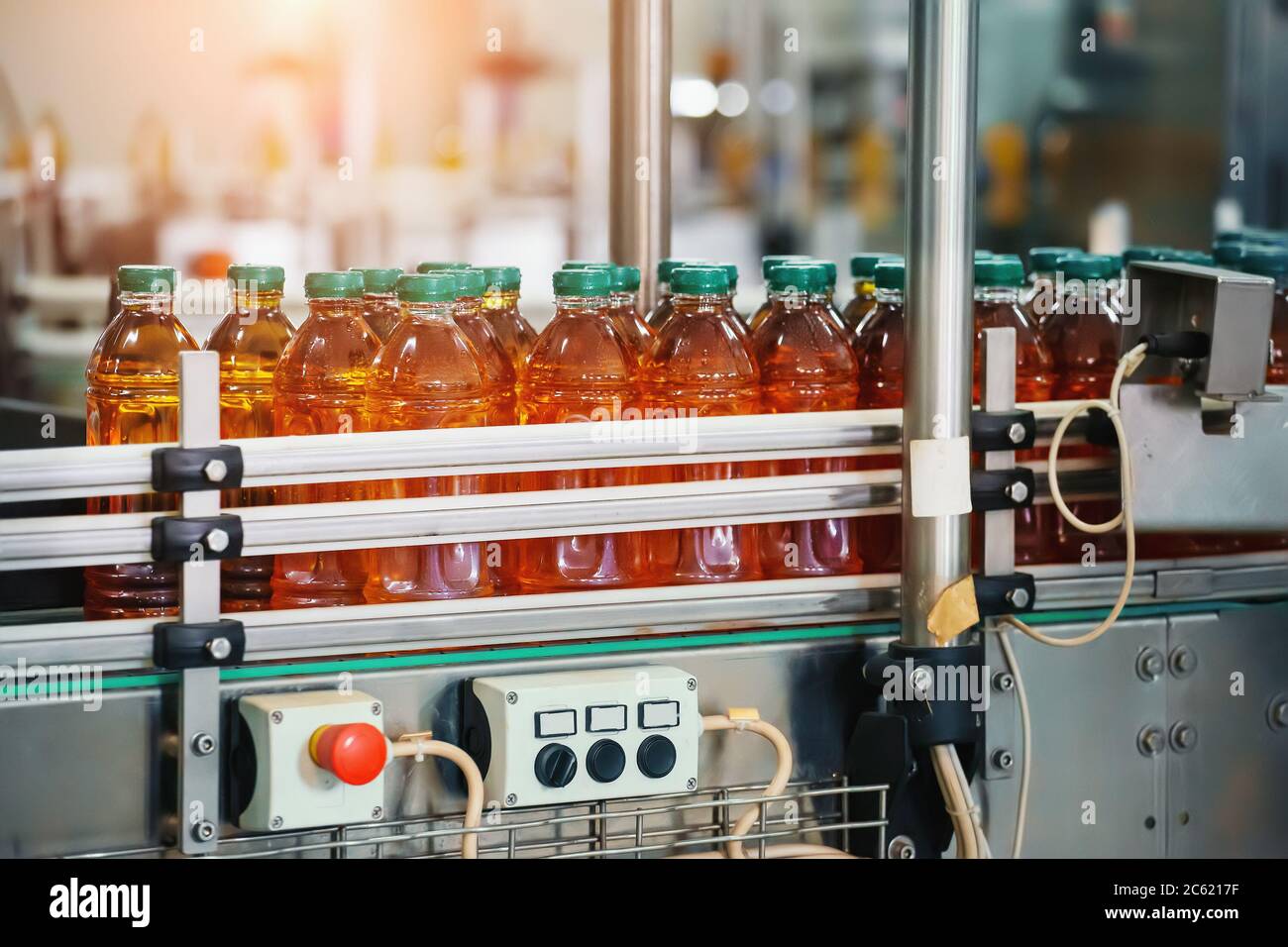 Juice in bottles on Conveyor belt, beverage factory interior, industrial production line. Stock Photo