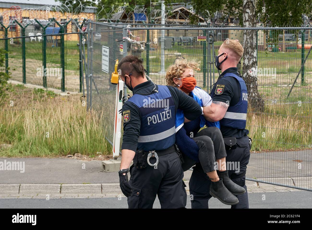 06 July 2020, Rhineland-Palatinate, Büchel: Police officers carry demonstrators who are blocking the main gate of the Büchel air force base to the side. About 100 participants from Germany and the Netherlands have joined a five-day protest, which is scheduled to end on this Tuesday (July 7). According to unconfirmed information, the last 20 or so US atomic bombs are lying in Germany at the air base. Photo: Thomas Frey/dpa Stock Photo