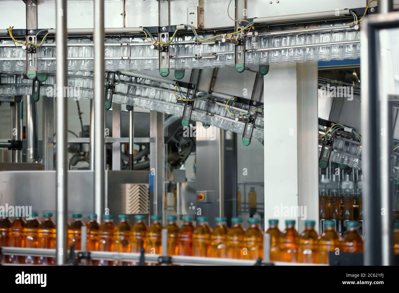 Plastic bottles with juice on conveyor line or belt in modern beverage factory. Stock Photo