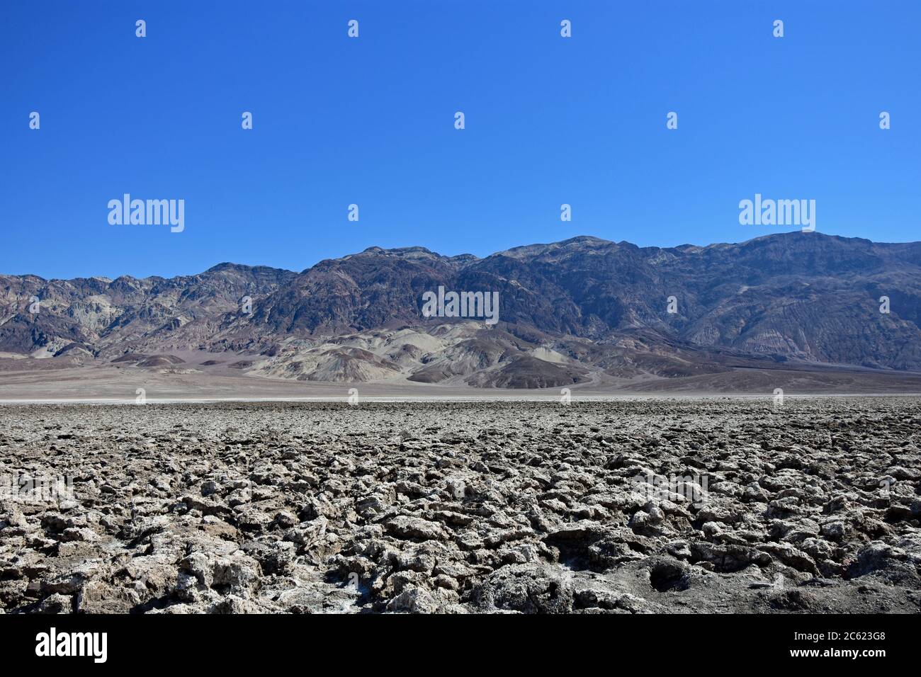 Devils Golf course in Death Valley National Park. Sharp and jagged salt crystals rise from the ground on a clear day with mountains in the background. Stock Photo
