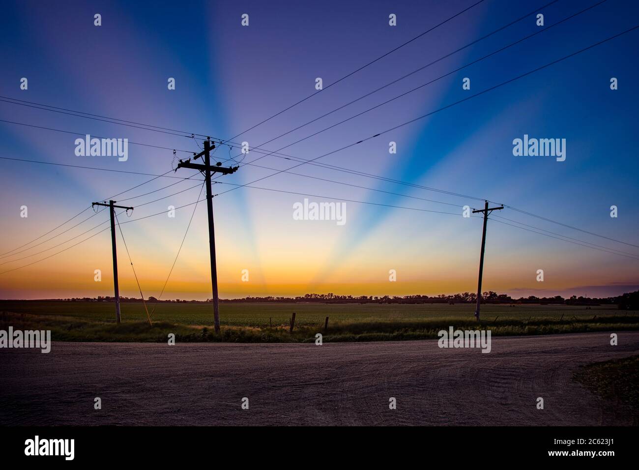 Colorful beams of light at sunset with three utility poles - a modern day Calgary Stock Photo