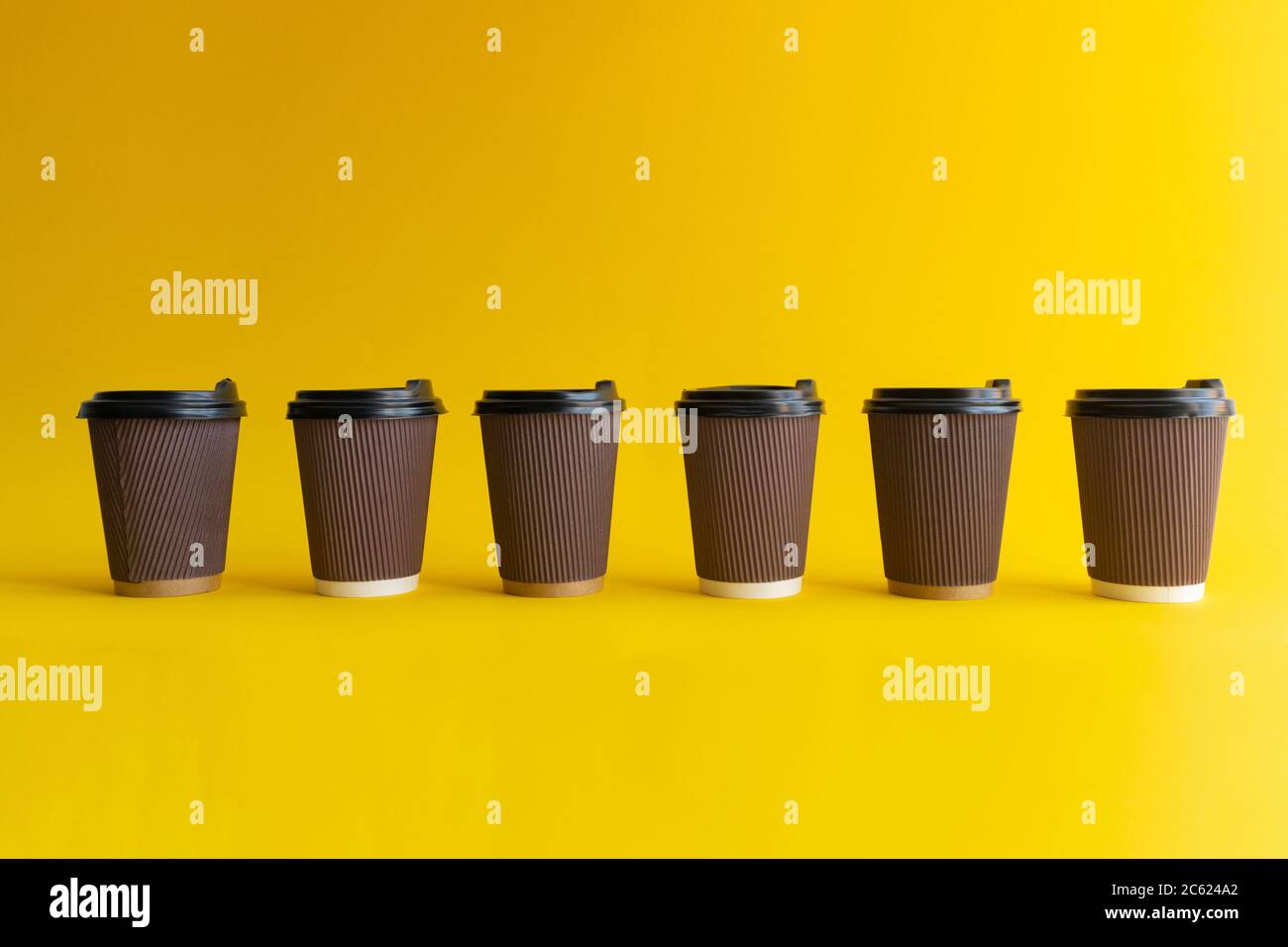 Six takeaway coffee cups with plastic covers, one cup differs from others Stock Photo