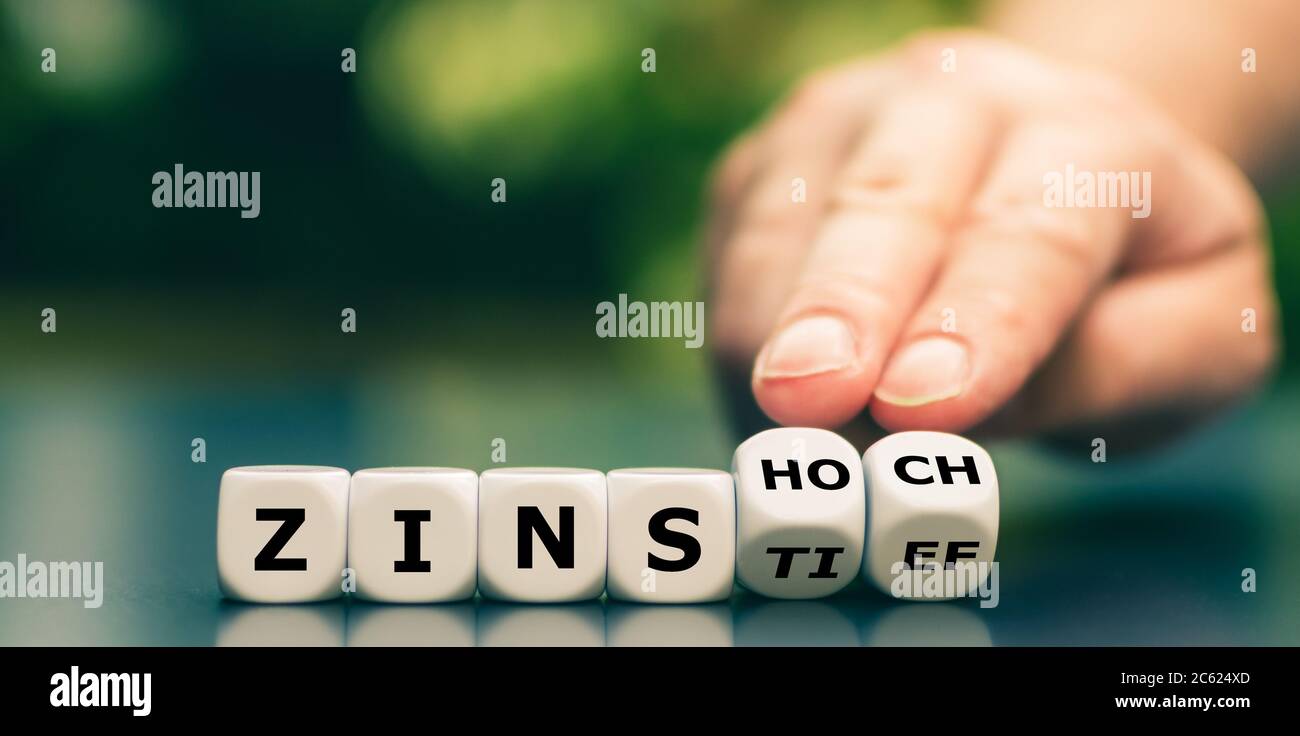 Hand turns dice and changes the German expression 'Zinstief' (low of interest rates) to 'Zinshoch' (peak of interest rates). Stock Photo