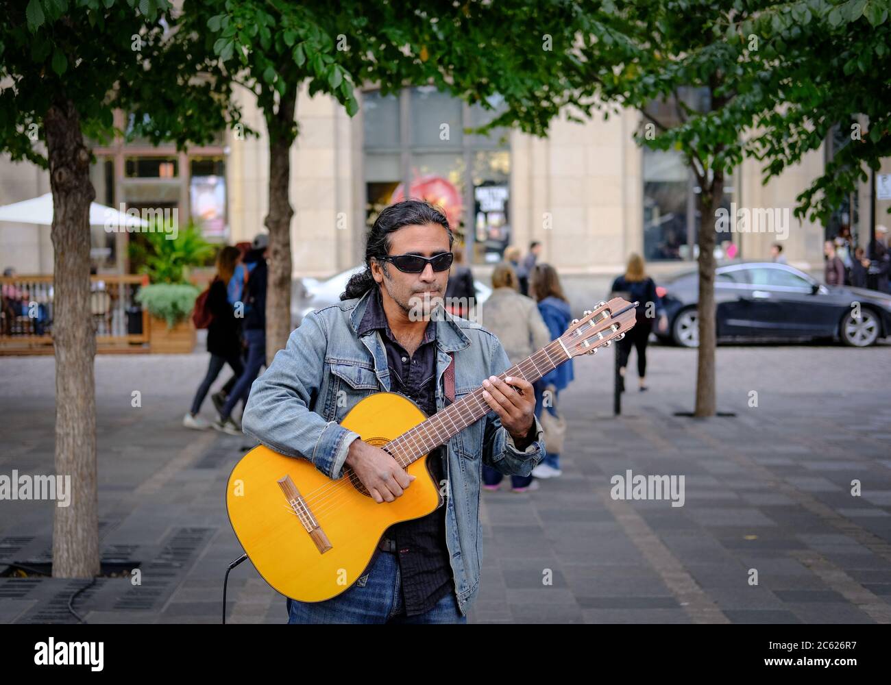 Fine acoustic guitarist playing to members of the public on busy