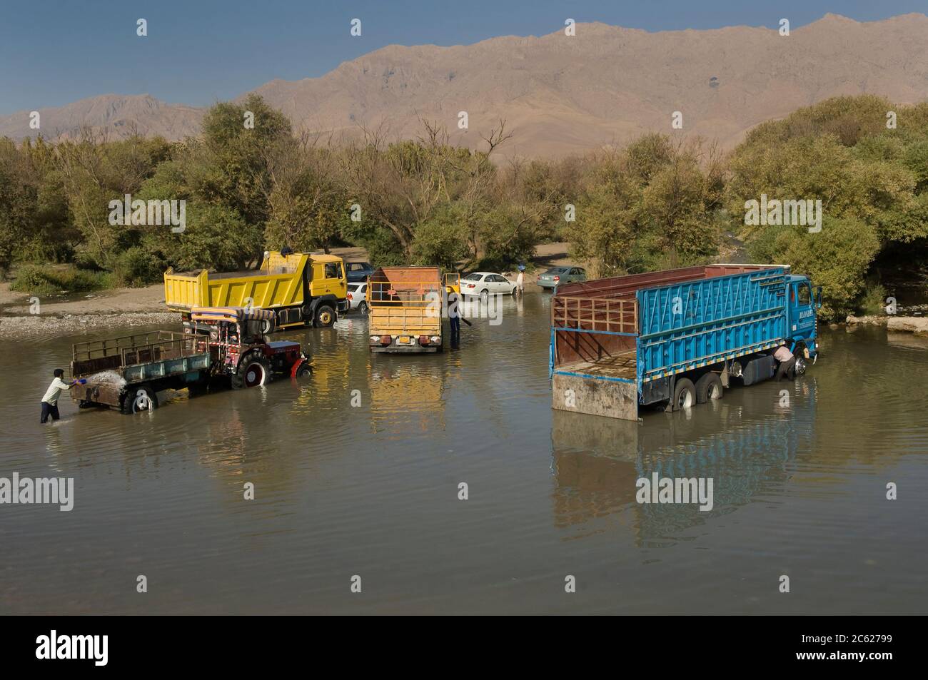 Halabja, North Iraq. October 5th 2009  Trucks and tractors being washed in the river on the road to Halabja, Kurdish North Iraq. Stock Photo