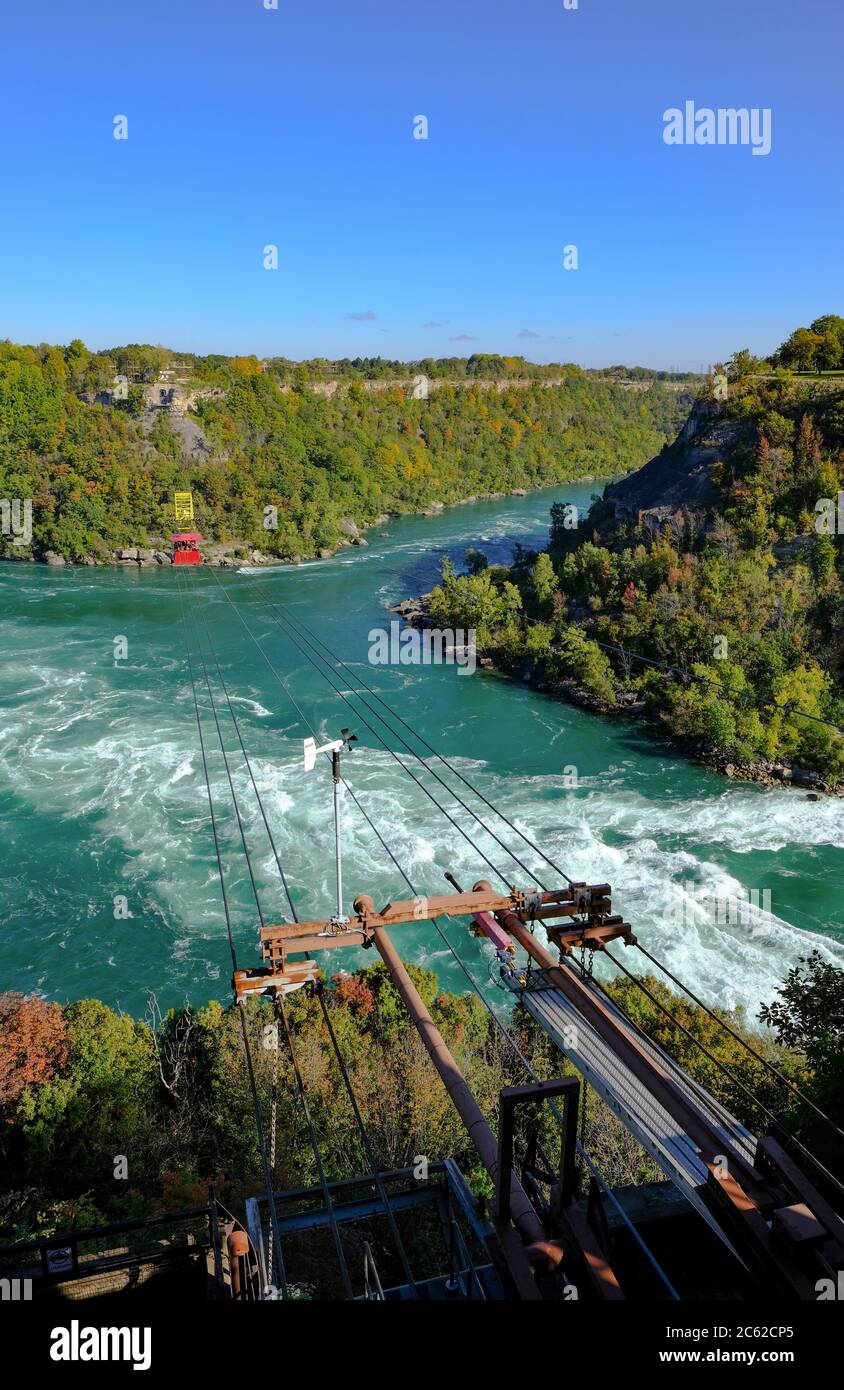 Scenic view of a cable car and its equipment seen passing with passengers near the wild rivers of Niagara falls in autumn. Stock Photo