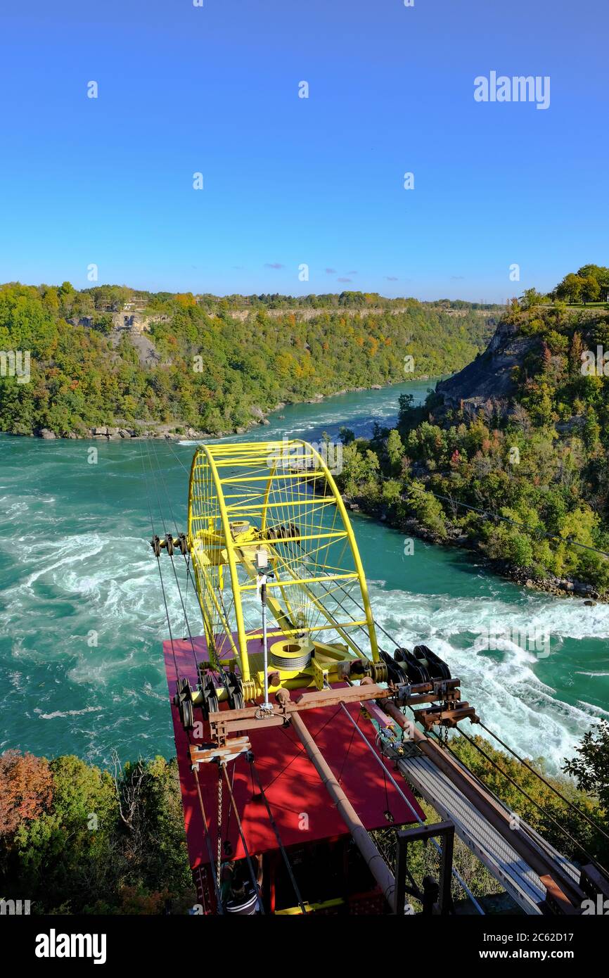 Scenic view of a cable car and its equipment seen passing with passengers near the wild rivers of Niagara falls in autumn. Stock Photo