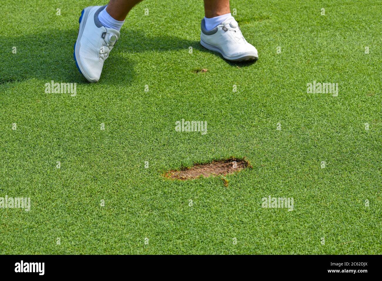 Young Man leaving a Divot cut out of the ground in the course of playing a stroke. Stock Photo