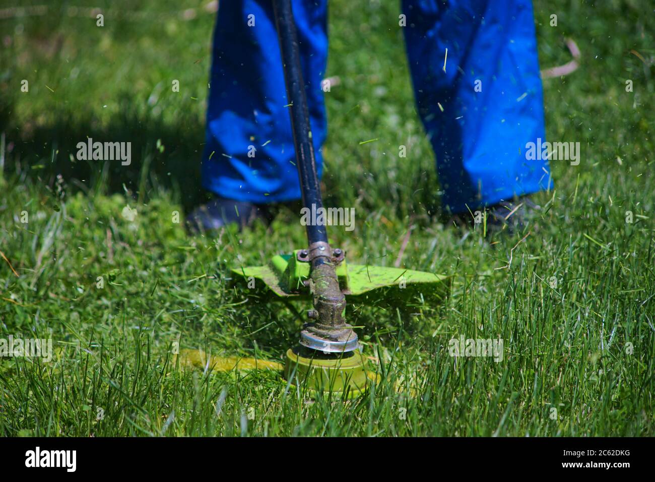 A man mows grass near his house with an electric mower Stock Photo