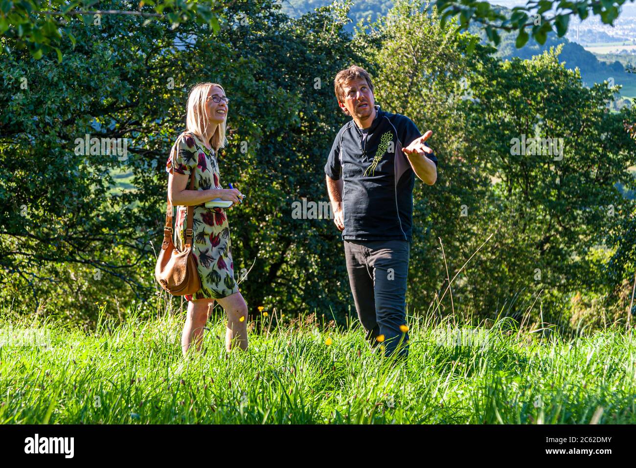 Jörg Geiger explains his commitment to nature conservation and organic diversity to food editor Angela Berg in a meadow orchard in Schlad, Germany Stock Photo