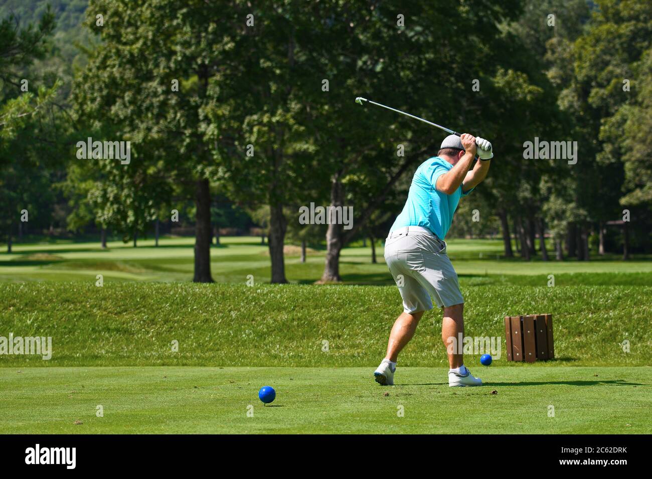 Young Man on Golf Course Hitting an Iron off the Tee Box While Playing a Round of Golf Stock Photo