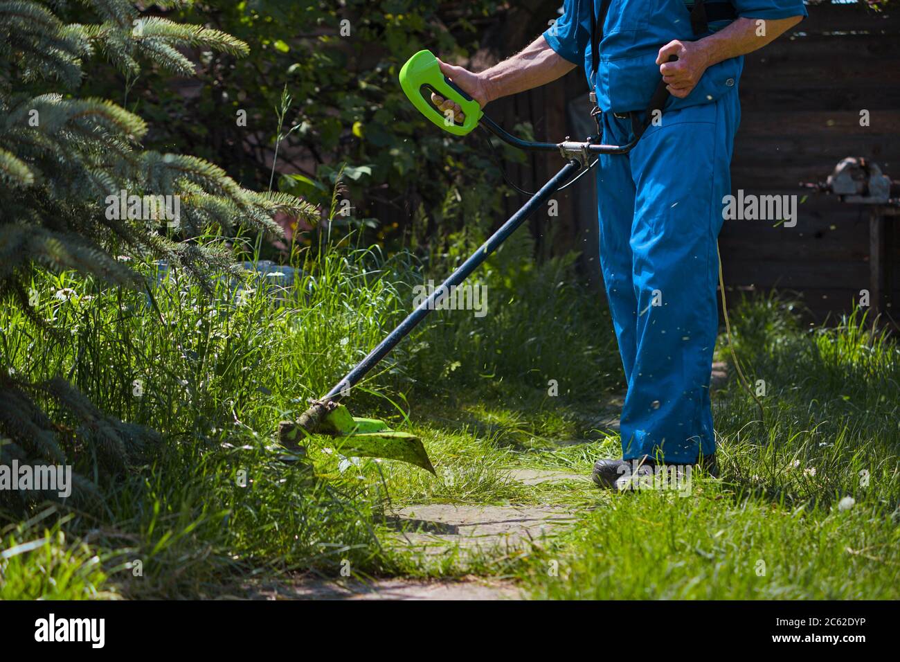 A man mows grass near his house with an electric mower Stock Photo