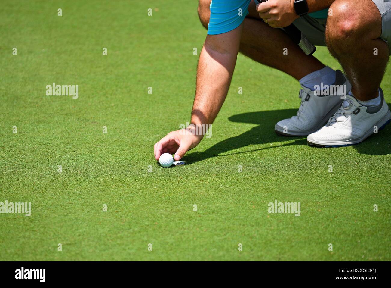 Young Man Kneeling Down and Placing his Golf Ball and Marker on the