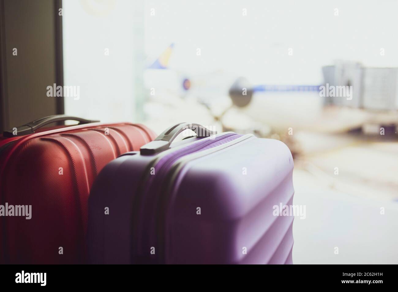 Couple of suitcases in airport, against the view on plane parked Stock Photo