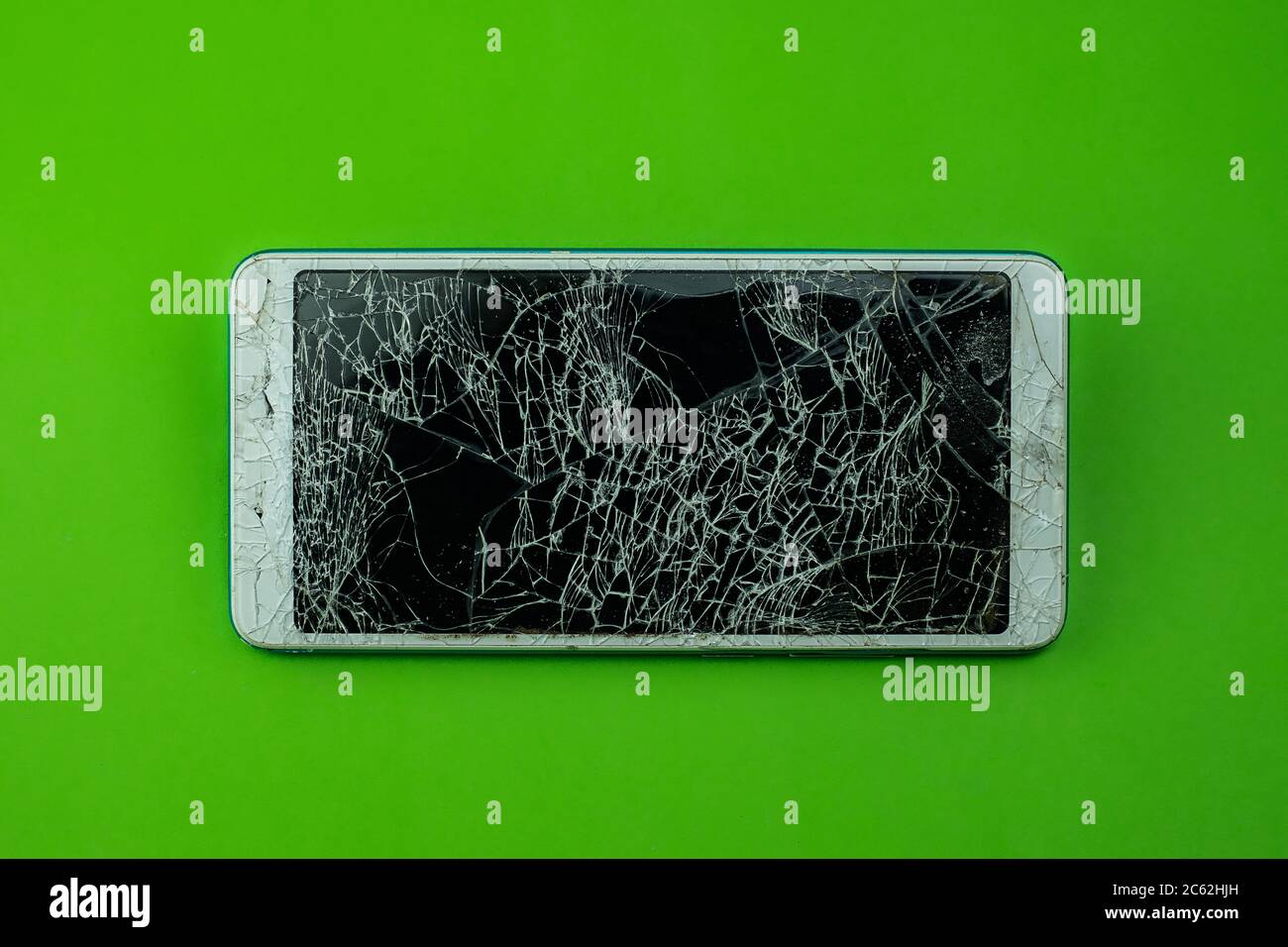 Smartphone screen is cracked on green background Stock Photo