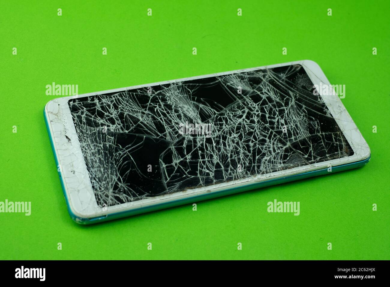 Smartphone screen is cracked on green background Stock Photo