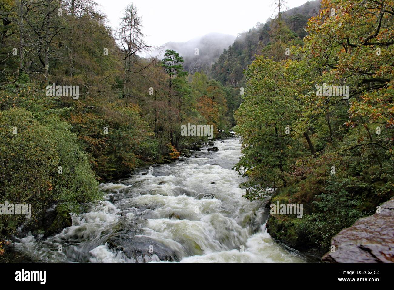 The Afon Glaslyn river in Snowdonia Mountain Range near to Beddgelert, North Wales, in full flow on a wet, windy, and wild Autumn day with pouring rai Stock Photo