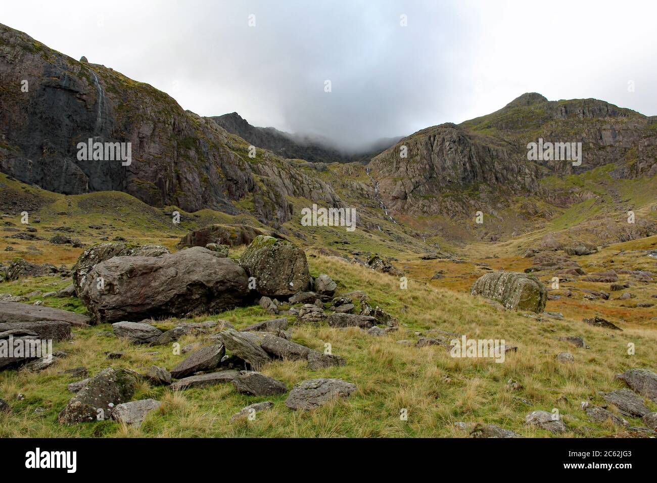 Typical Snowdonia mountain range scenery looking up from Ynys Ettws towards Clogwyn with Snowdon shrouded in cloud in North Wales on a Sunny Spring Da Stock Photo