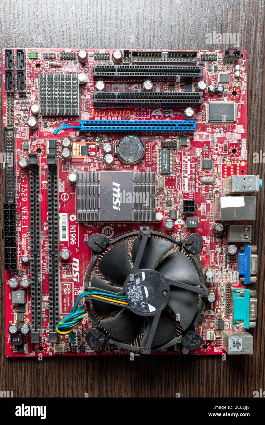 Ukraine - April 25, 2020: Computer motherboard with CPU coller on brown background. Hardware components. View inside, background Stock Photo