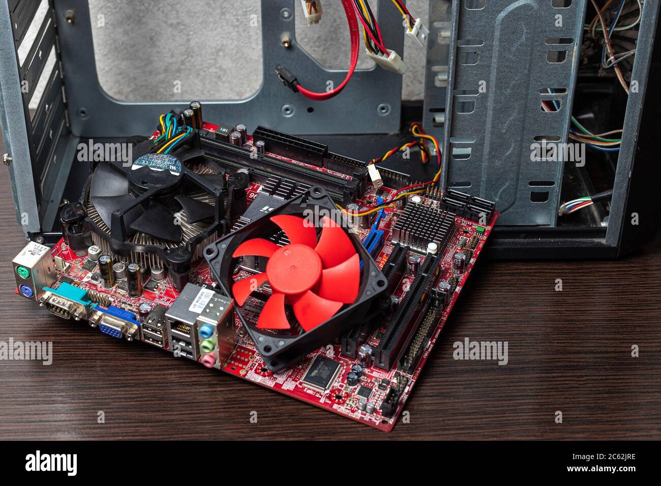 Ukraine - April 25, 2020: Replacement of CPU coller. Computer motherboard with CPU coller near the case on brown background. Hardware components, back Stock Photo