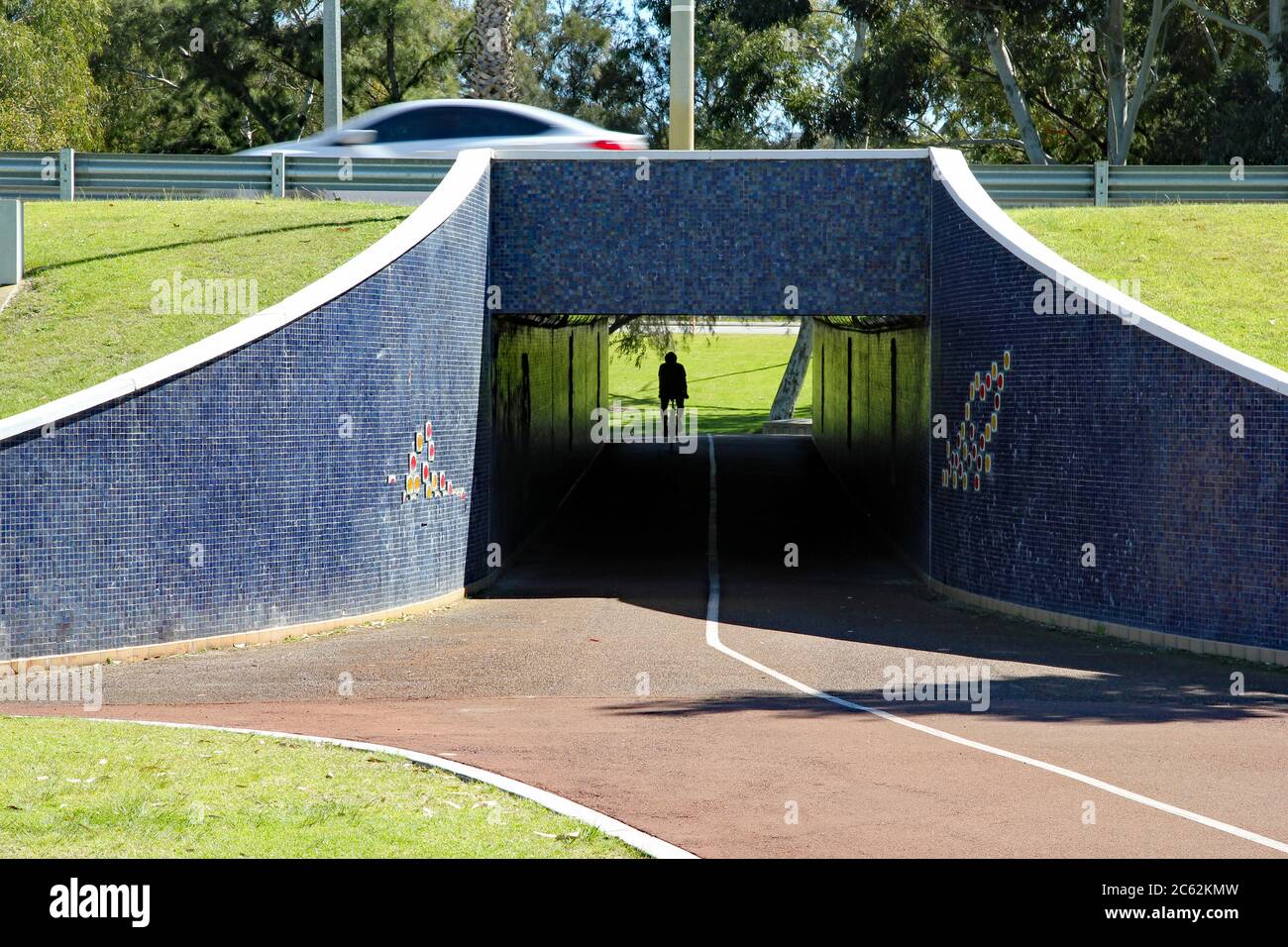 In Perth, Western Australia, the silhouette of a cyclist emerges on the other side of a tunnel under a road on one of the cities excellent segregated Stock Photo