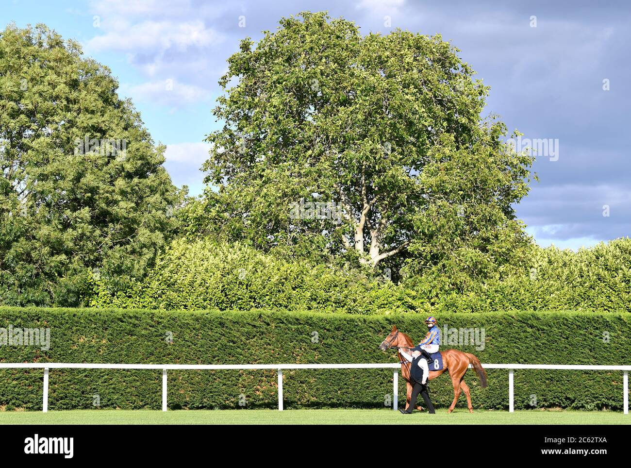 A horse is walked to the track by a stable hand at Windsor Racecourse. Stock Photo