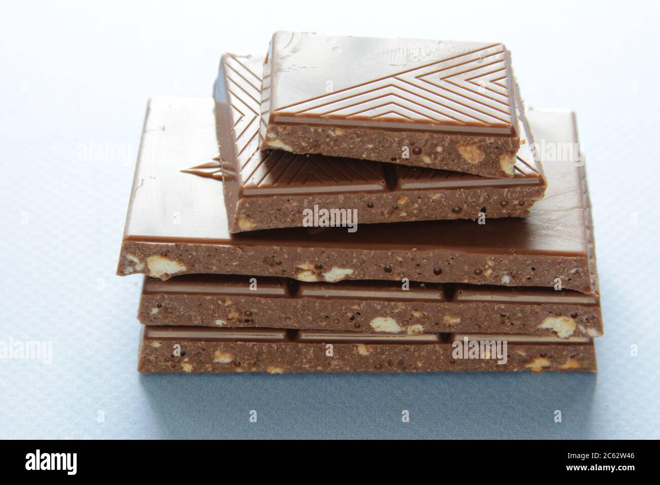 Milk chocolate pieces isolated on blue background from top view. Close ...
