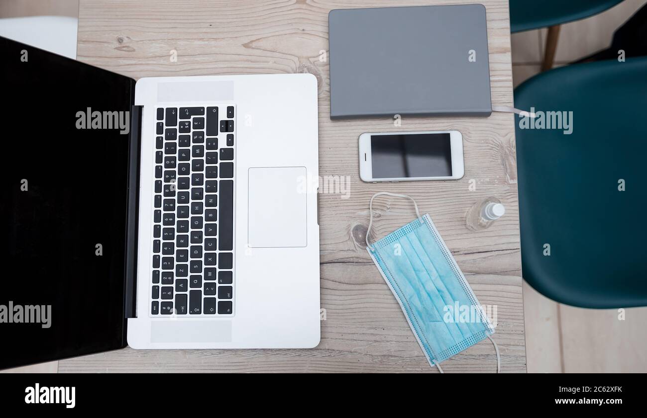 laptop, smartphone and protective mask on the office Desk Stock Photo ...