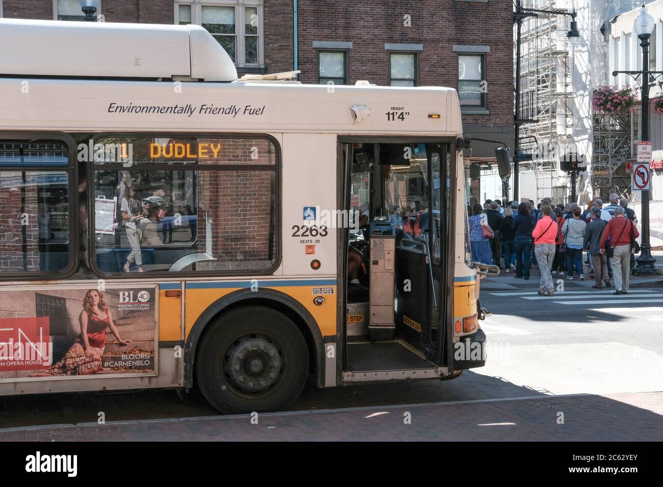 Local Harvard bus seen stopping near the University Campus, with members of the public having disembarked and seen walking in the distance. Stock Photo