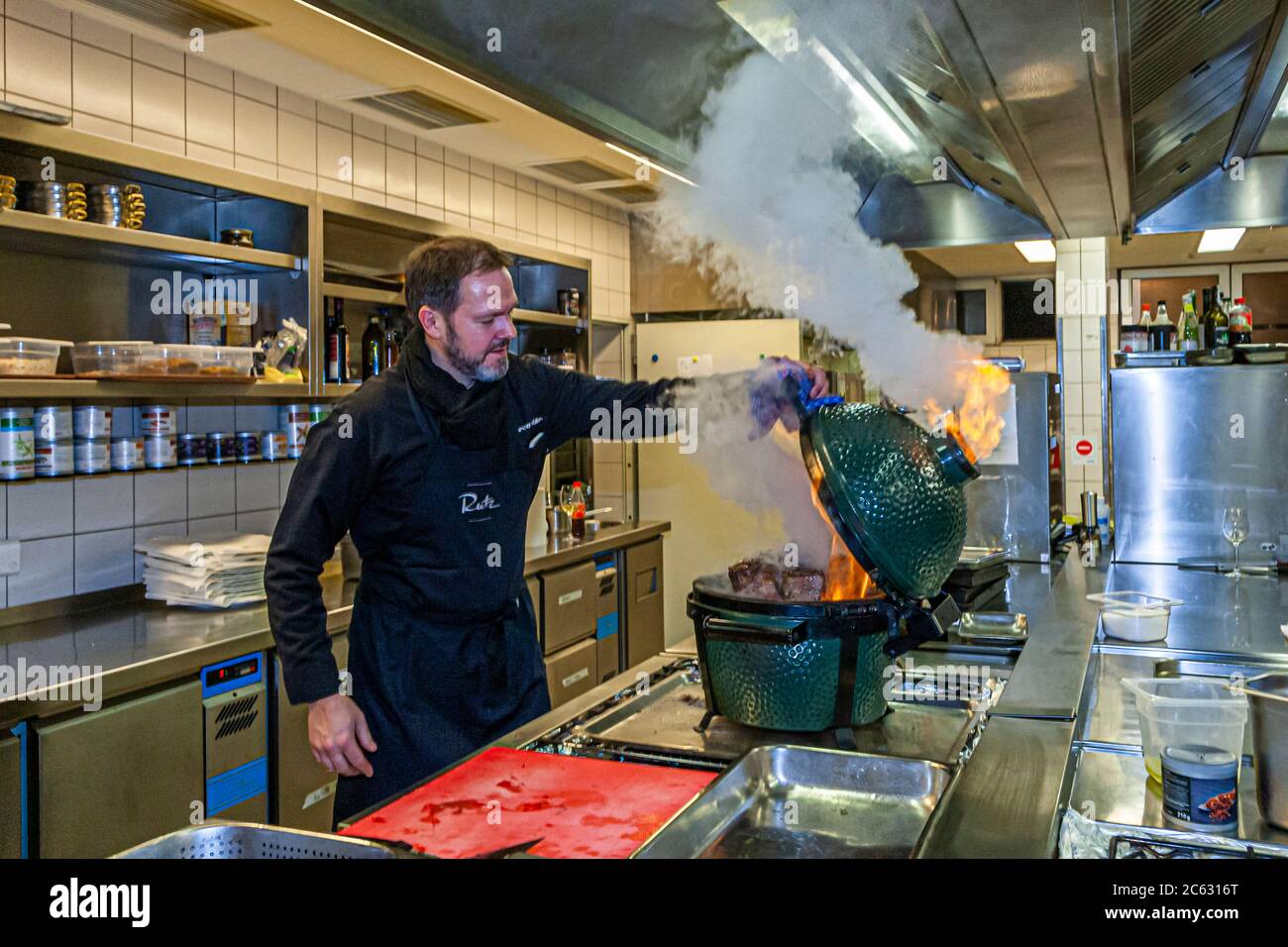 German 3 Michelin star chef Marco Müller with Big Green Egg. One of the secrets of tender beef brisket is the "reverse" order: first heat it in the oven at low heat and then grill it hot in its own smoke just before cutting it Stock Photo