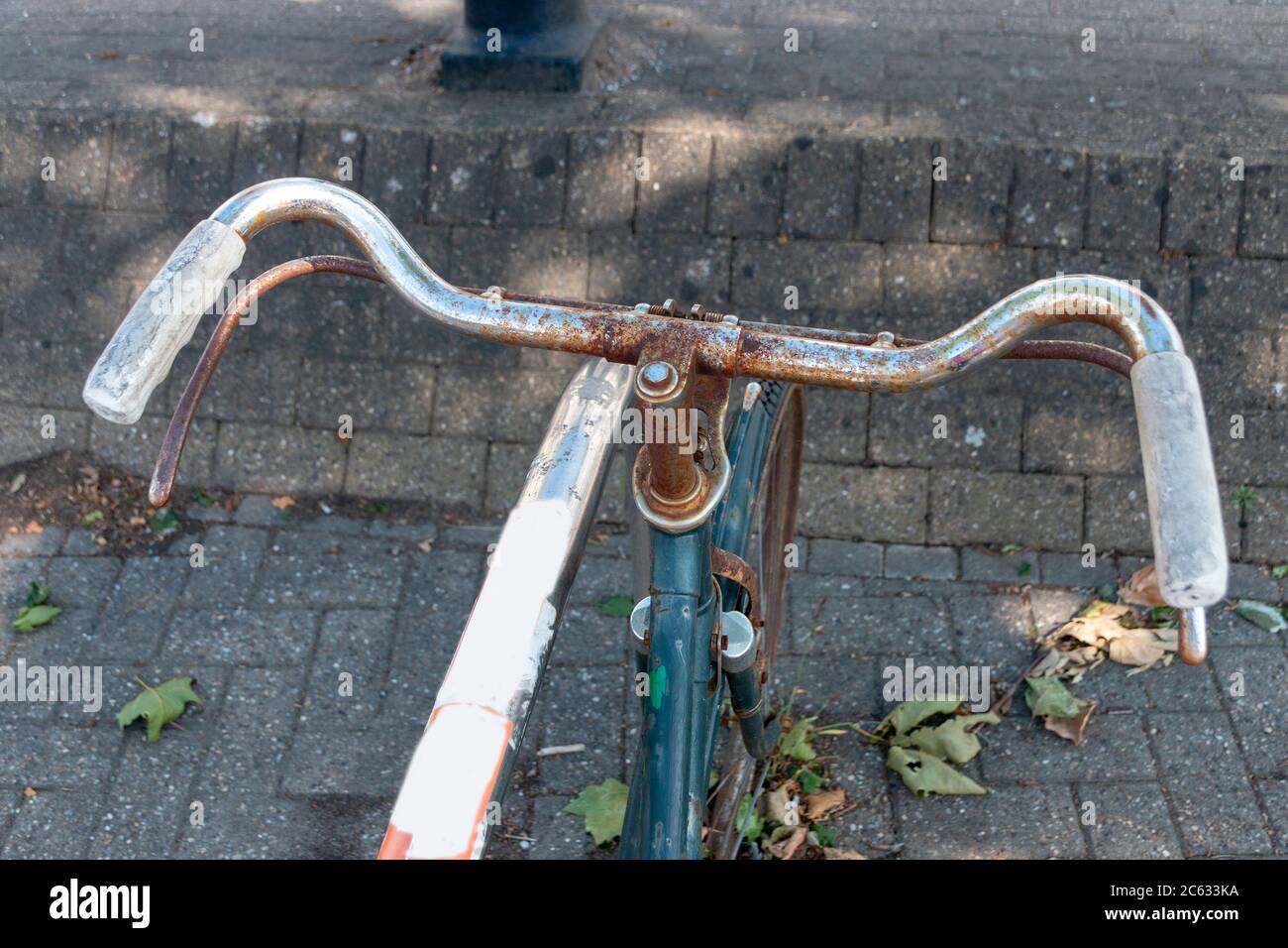 a close up view of a rusted old bicycle that has been abandoned and locked to a bike rake in the city Stock Photo