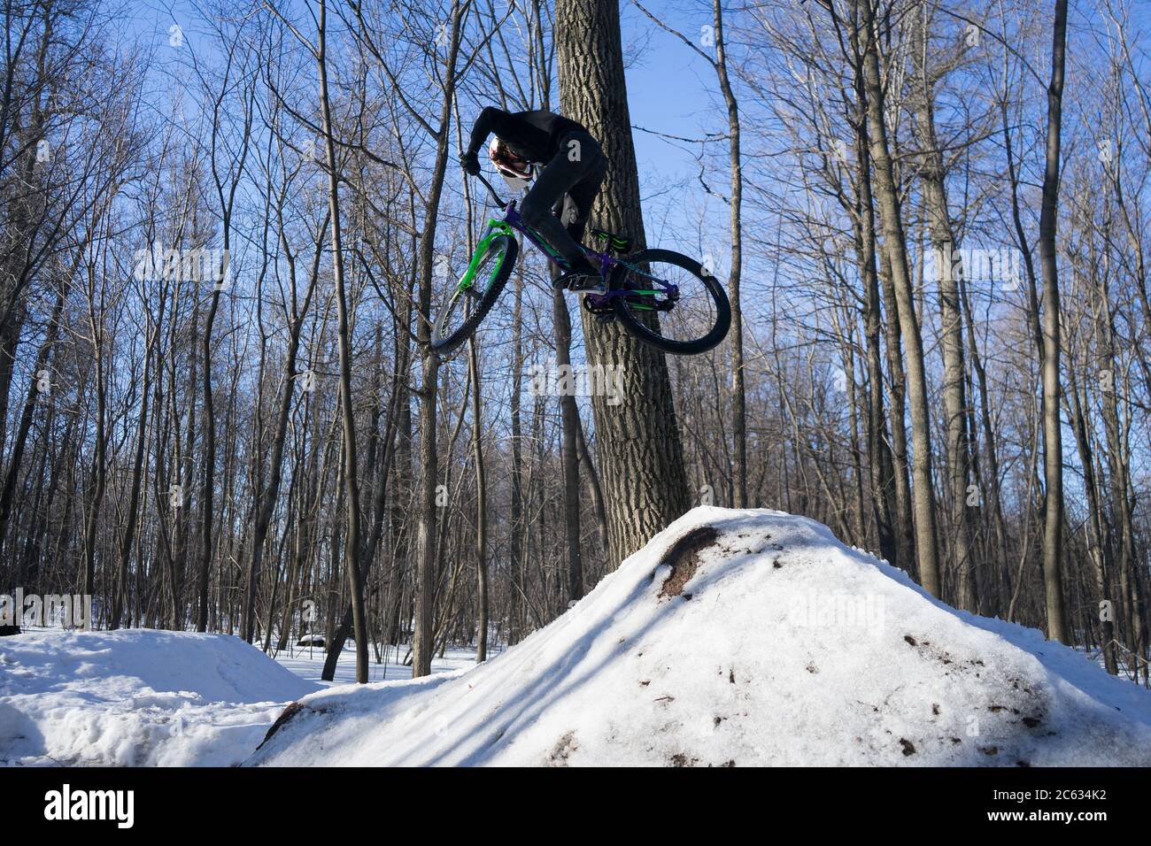A cyclist does a 360 trick on a springboard in winter. Athlete shows a trick  Stock Photo
